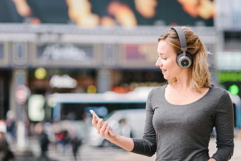 lifestyle product photo of a model wearing Orosound headphones in Paris with a busy Parisian street behind her