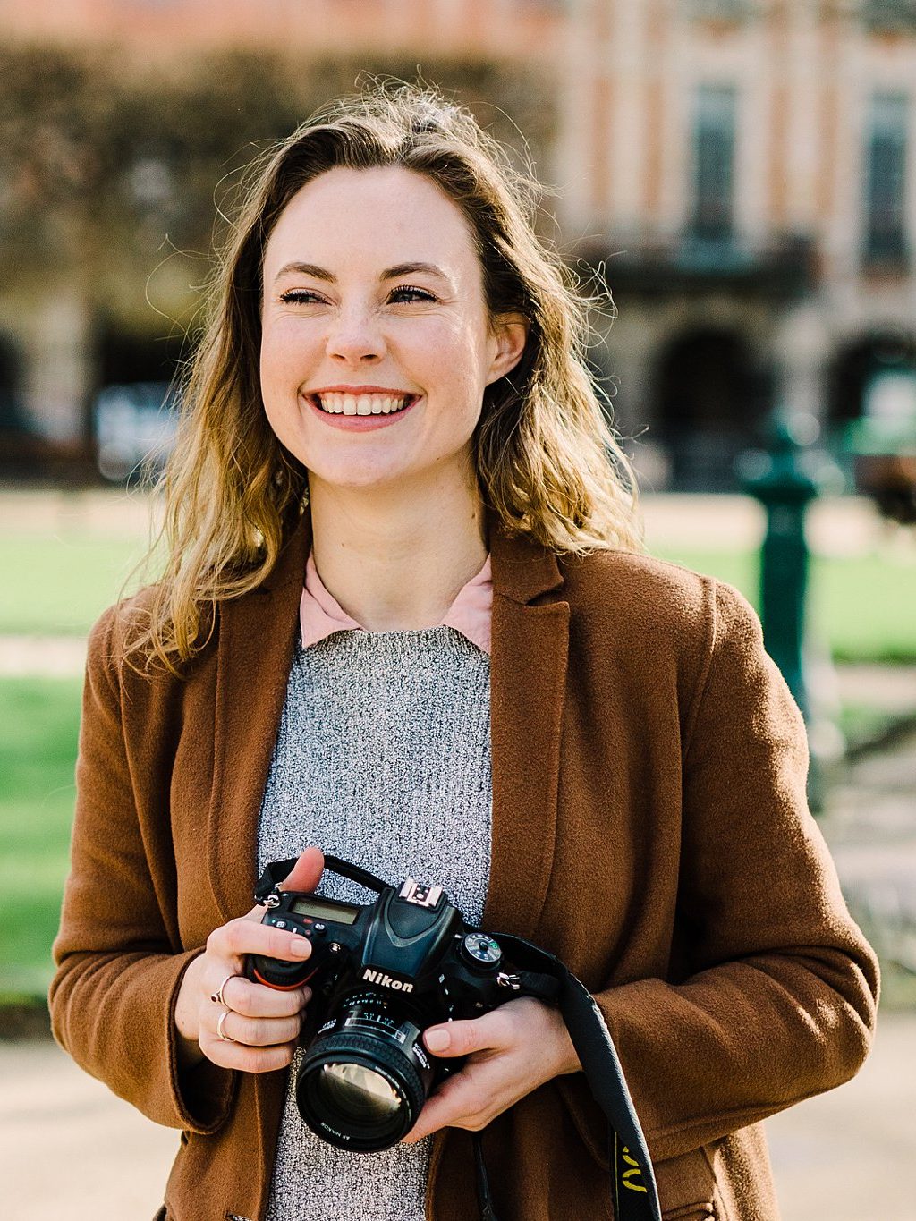 portrait of Paige Gribb, a photographer in Paris France, holding a Nikon Camera and smiling