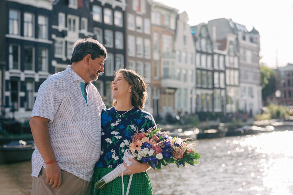 A couple celebrates their 20th anniversary with an Amsterdam photo shoot, with colorful buildings and water in the background.
