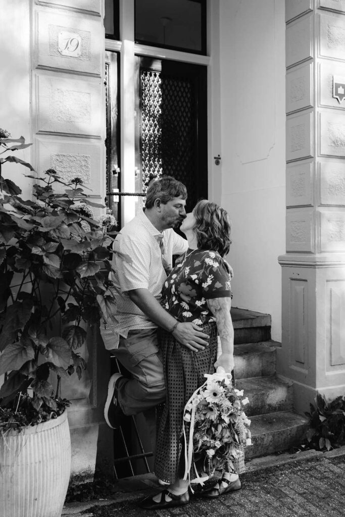 Black and white photo of a couple holding each other and staring into each other's eyes in a doorway in Amsterdam
