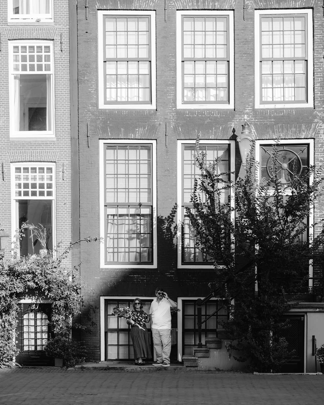 Black and white photo of a couple standing in front of a brick building